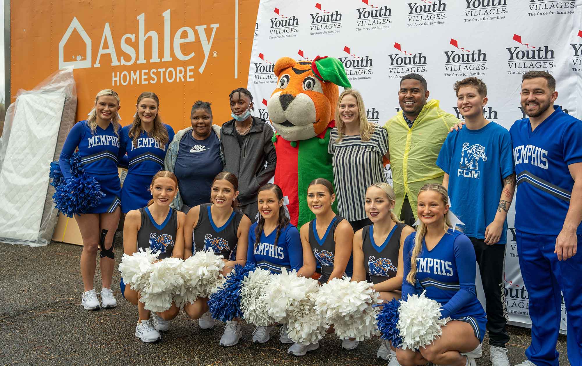 Ashley_Home_Bed_Giveaway_1216 Youth Villages staff, University of Memphis Cheer team, and Intercept family in front of Ashley Home Furniture truck