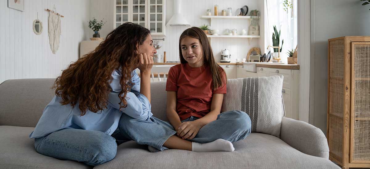 Yv-March-Pure-Living Mom and daughter sitting on couch smiling at each other