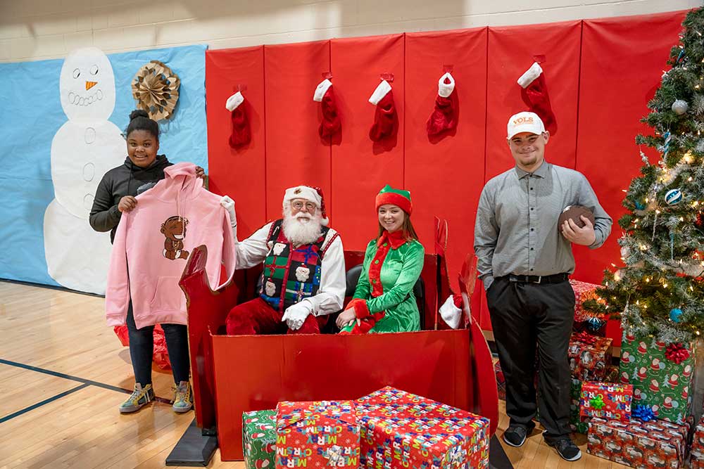 Dogwood_Holiday_Heroes_Party_2023 two youth posing with Santa and his elf at a Holiday Heroes Christmas party
