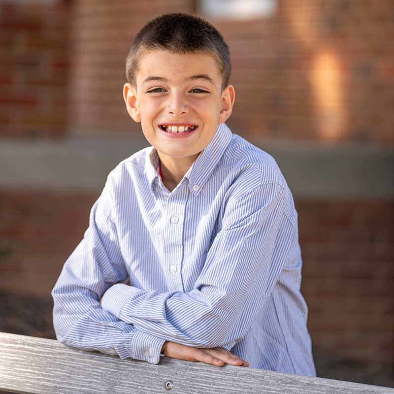Braiden-1 portrait of Braiden standing behind a bench