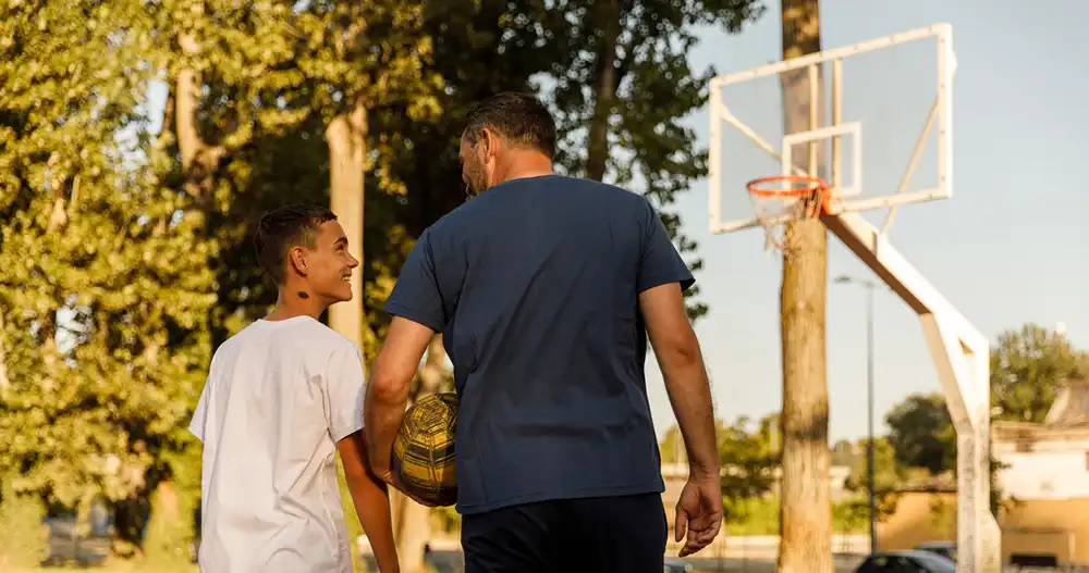 Youth and adult playing basketball young person and an adult playing basketball