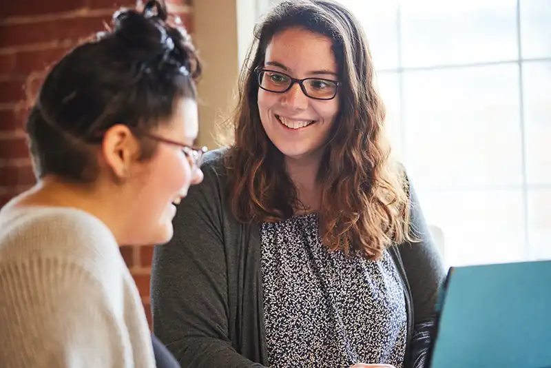 adult-with-young-women-smiling-at-computer young women with adult smiling at a computer