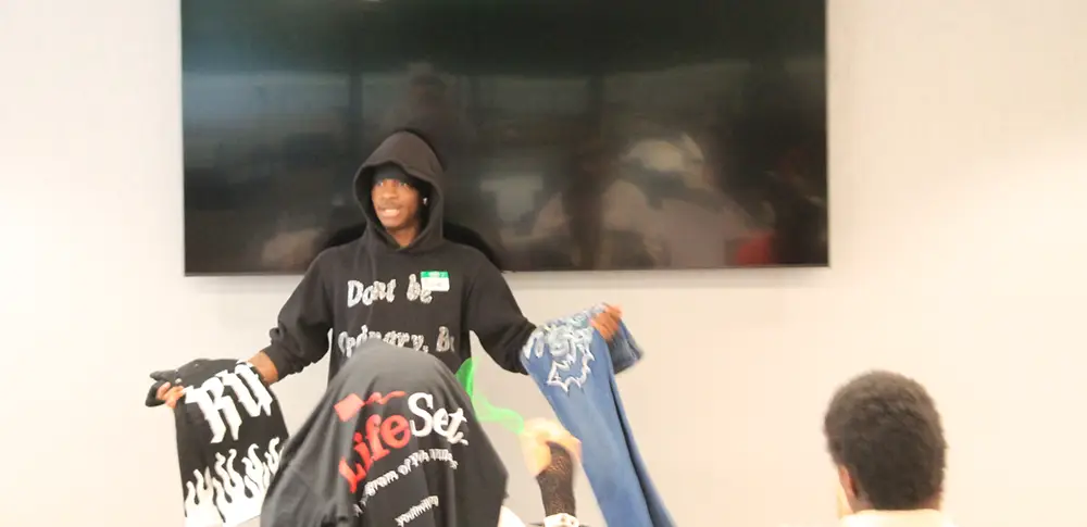 Charles-LifeSet-Georgia-2025 LifeSet participant Charles displays items from his custom clothing line
