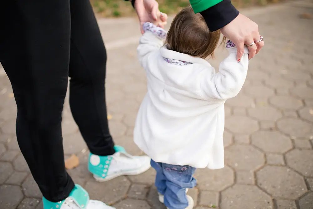 Mom holding daughter's hands walking