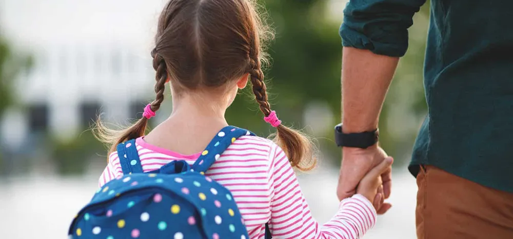 daughter-dad-holding-hands daughter carrying backpack holding dad's hand
